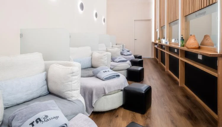 The Pentridge reflexology lounge — white recliners with TAO blankets receding down a warm wood-slat room